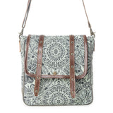 A square-shaped shoulder bag with a black and white mandala pattern on a light gray-green background, featuring brown faux-leather straps and metal studs, shown against a plain white background.