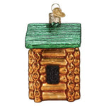 Glass ornament shaped like a log cabin with a green roof on a white background