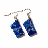 Blue marbled earrings on a white studio background