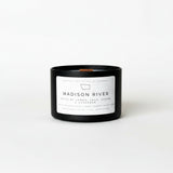 Black candle with a white label on a white surface and background