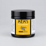 A jar of MEM'S Dry, Cracked Skin ointment  in a black jar with a black lid, featuring a yellow and white label.