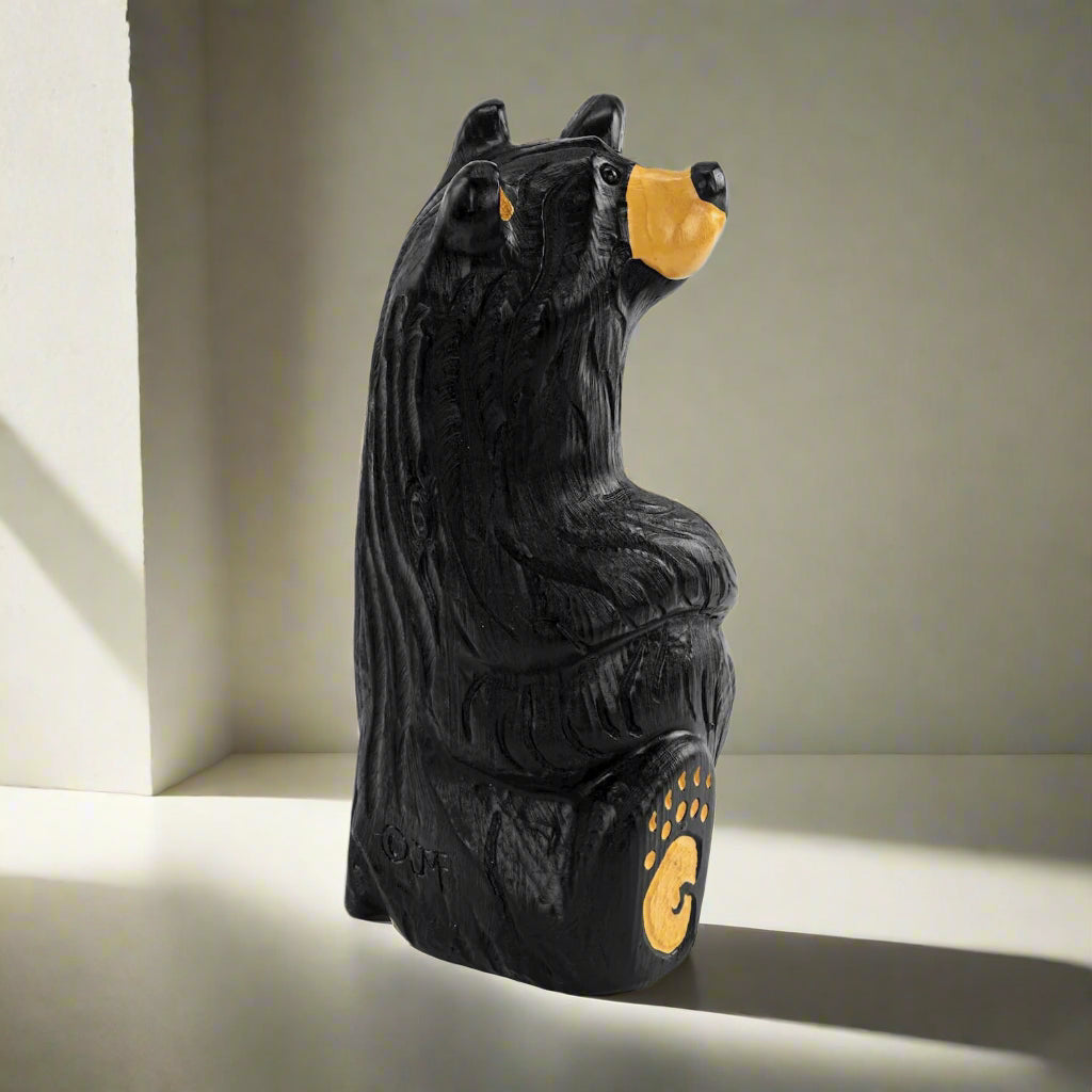Black bear figurine with yellow accents on a white background