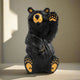 Black bear figurine with yellow accents on a white background