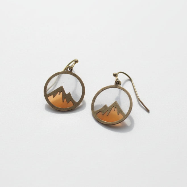 Pair of earrings on a white surface with a natural background
