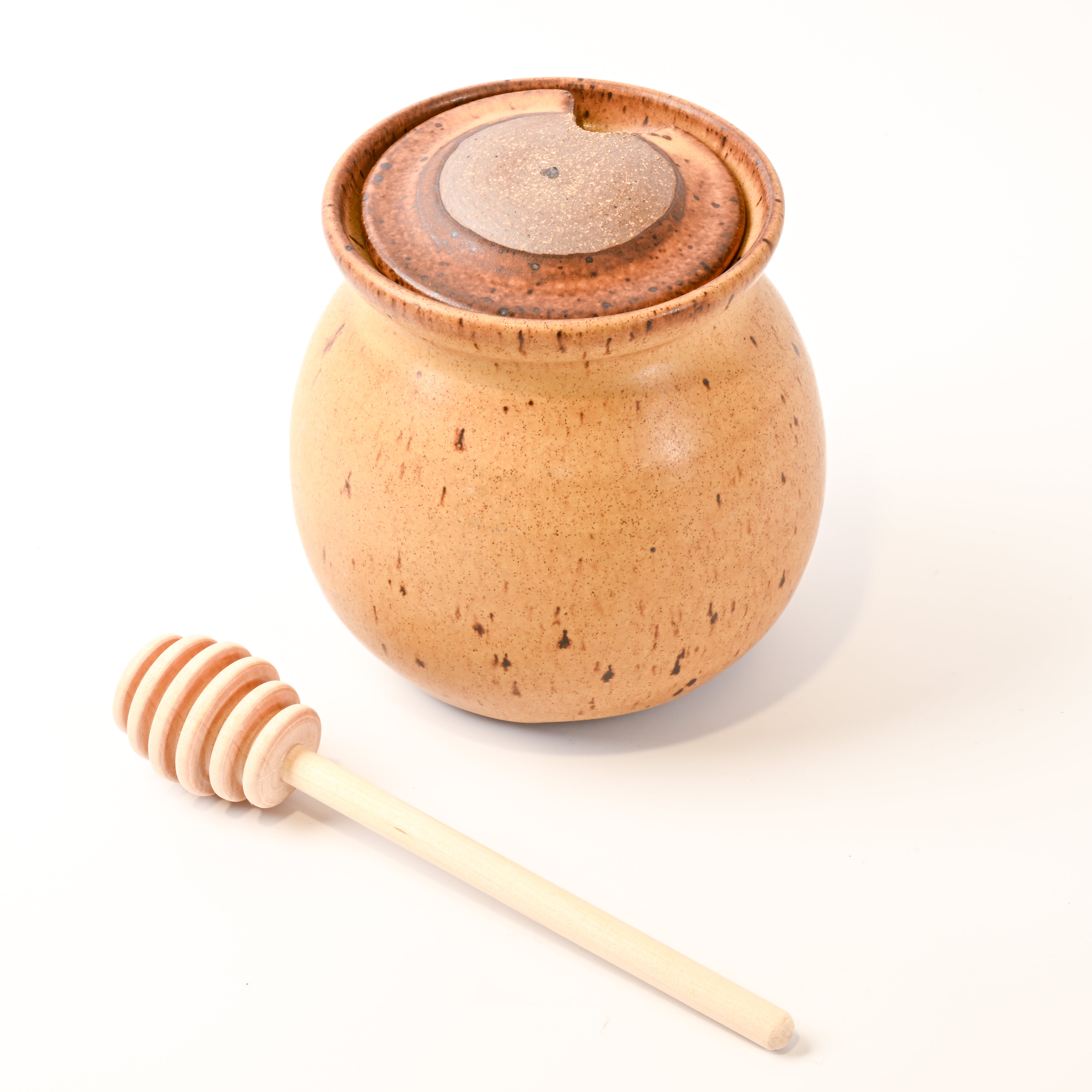 honey jar with wooden dipper on a white background