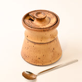 stoneware container with a lid and a spoon on a white background