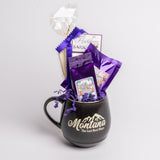 Black mug with 'Montana' branding filled with purple-themed treats on a light gray background