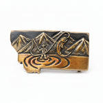Bronze belt buckle with mountain and nature design with a white background