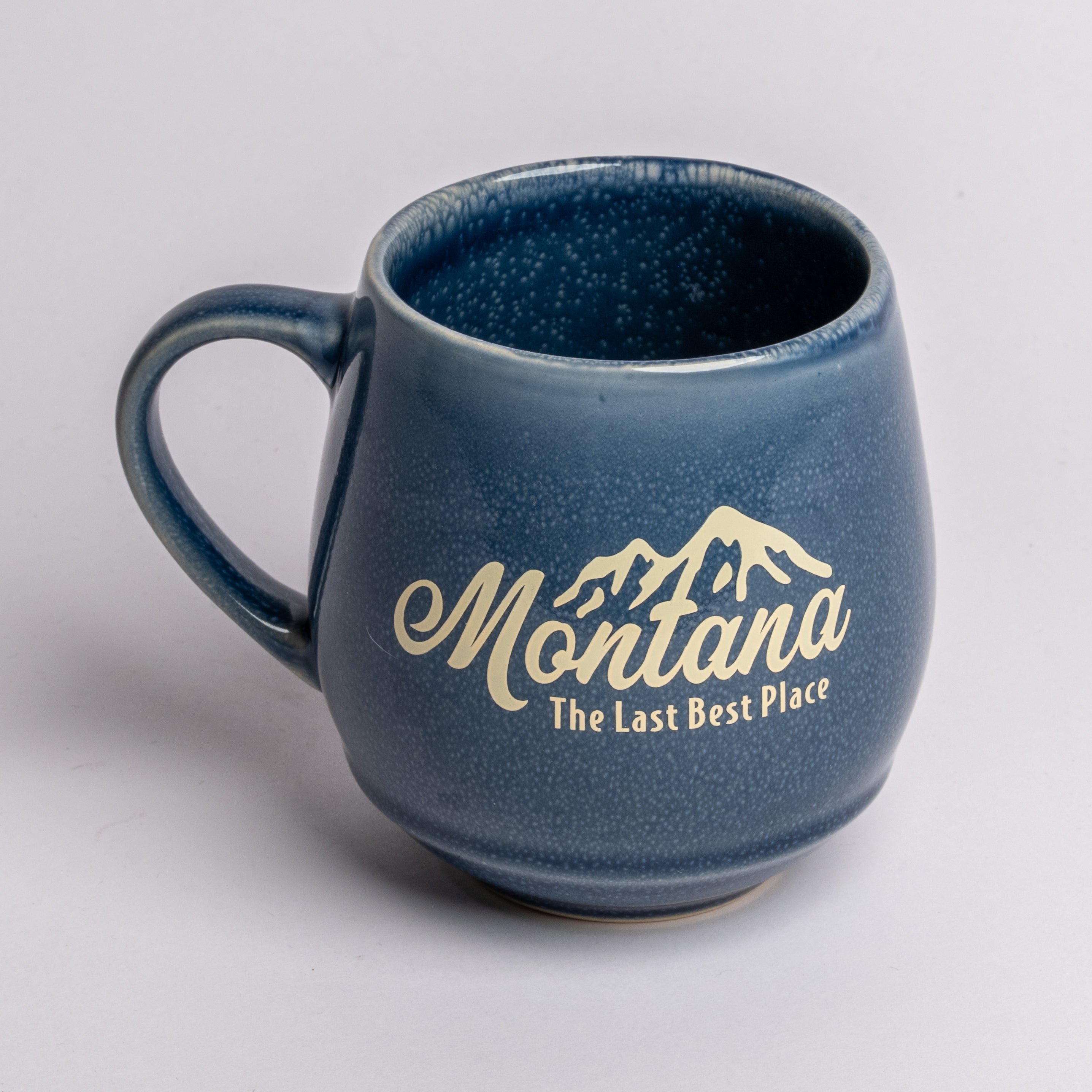 Blue mug with 'Montana The Last Best Place' text on a light gray background