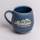 Blue mug with 'Montana The Last Best Place' text on a light gray background