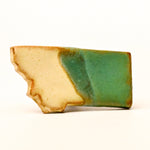 Ceramic magnet with green and beige colors on a white background