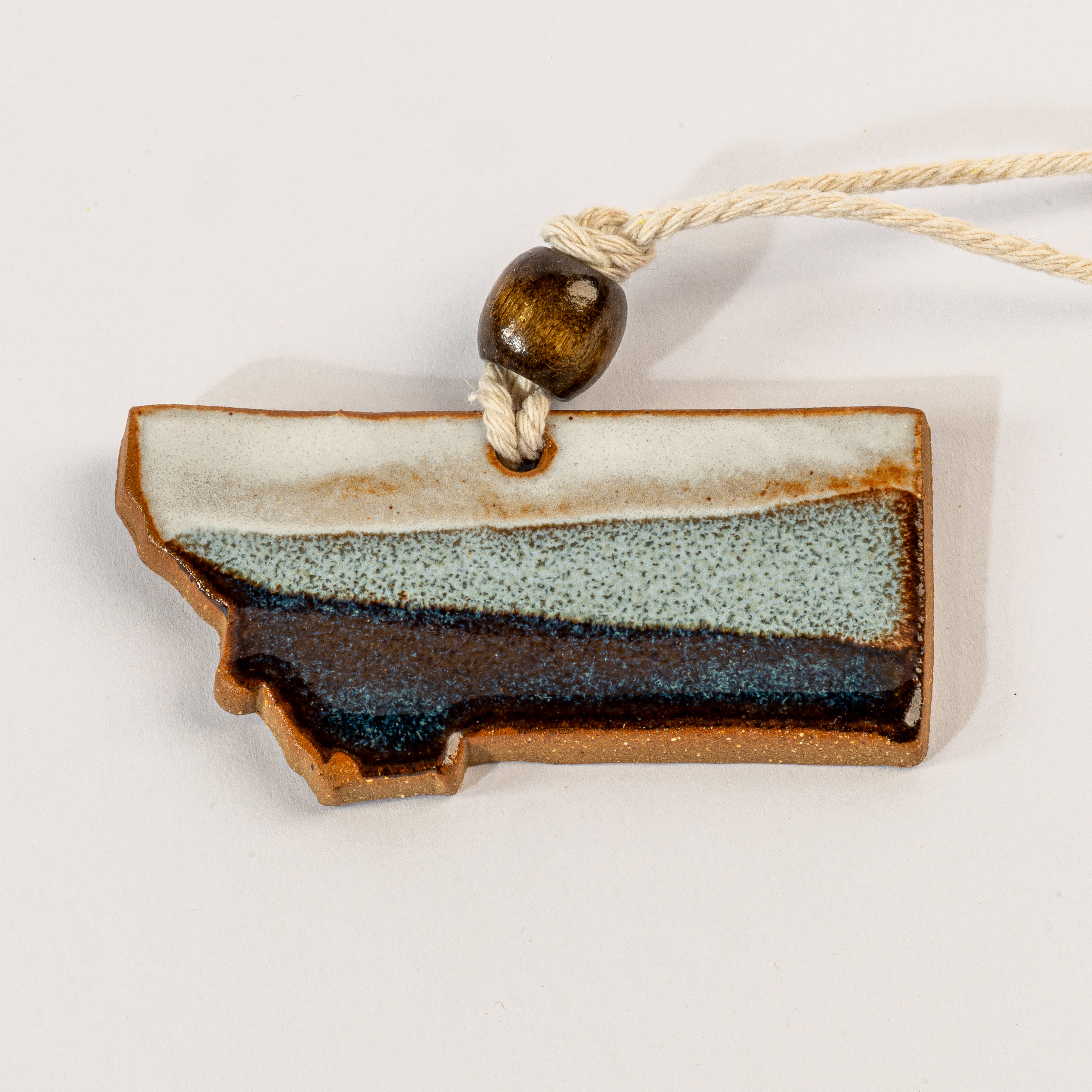 Ceramic ornament shaped like a state with a rope and bead on a white background