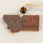Decorative sign shaped like the state of Montana with animal illustrations and 'Montana' text, hanging on a white background.