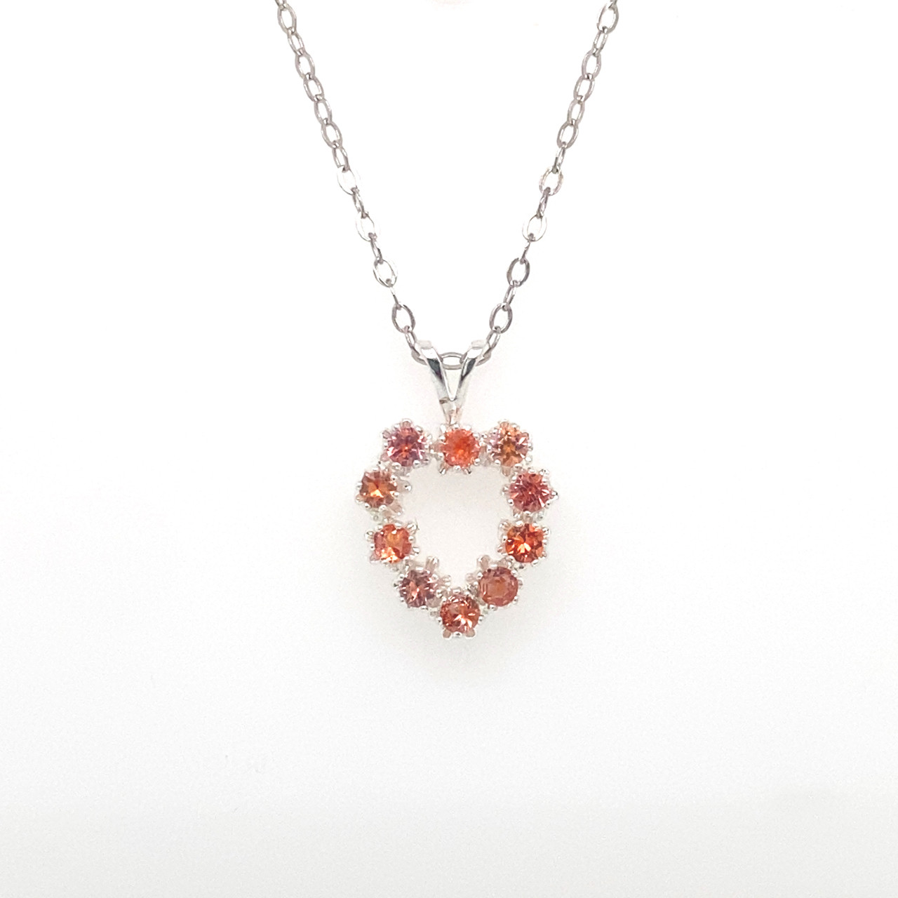Necklace with a heart-shaped pendant featuring red and orange Montana sapphires on a white background