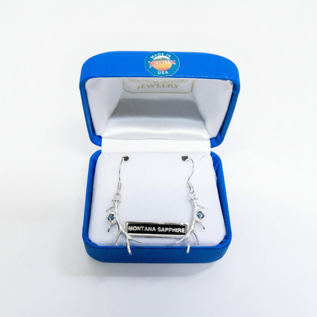 Silver earrings with Montana Sapphire in a blue jewelry box on a white background