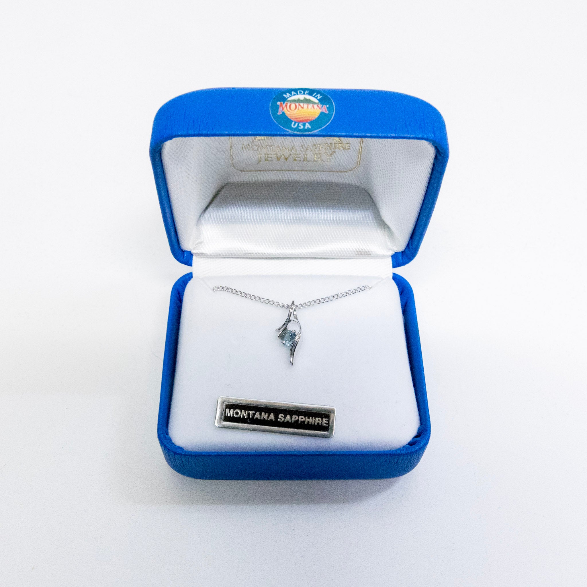 Jewelry box with a silver necklace featuring a Montana Sapphire pendant on a white background