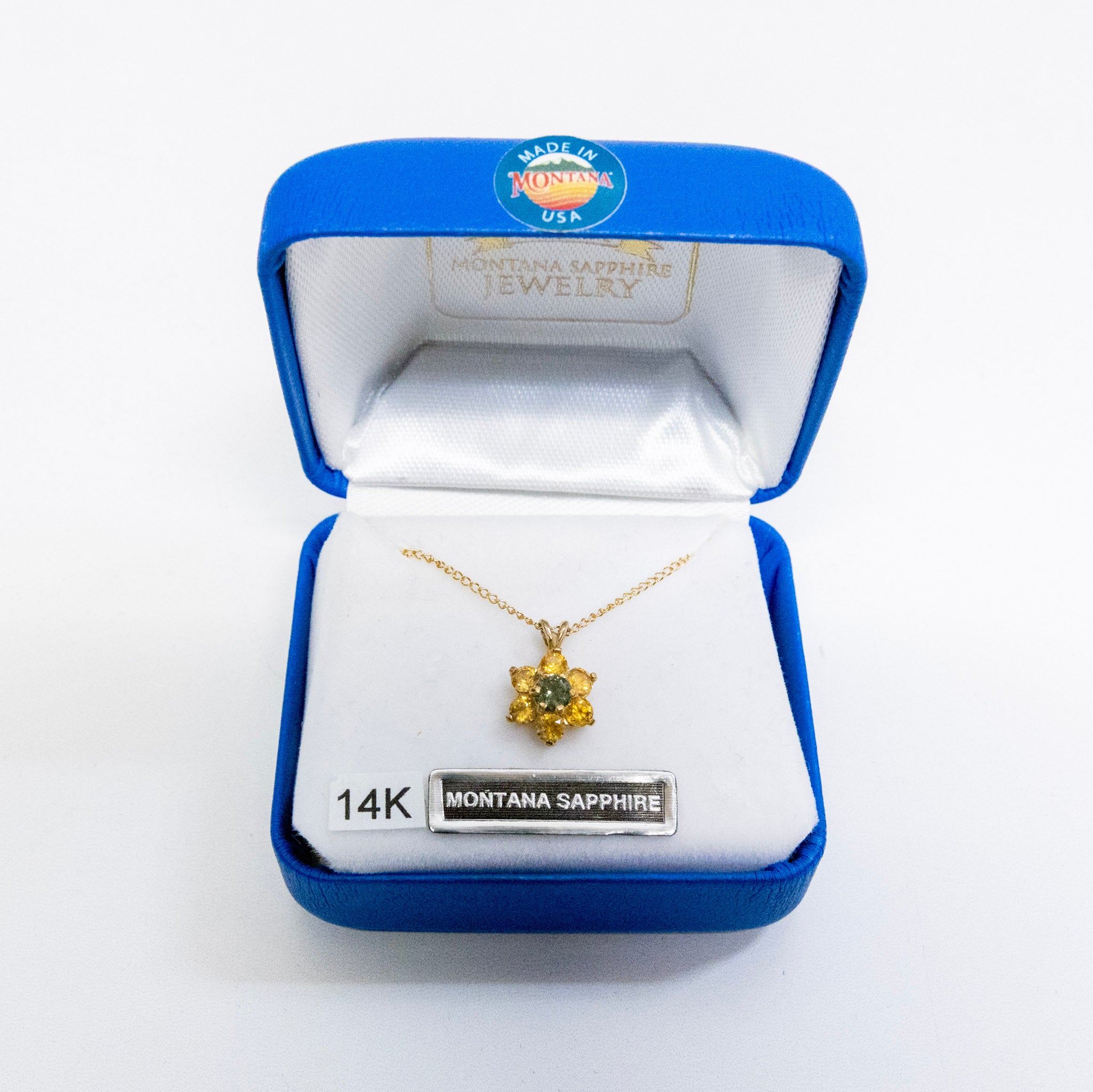 Gold necklace with pendant in a Montana Sapphire jewelry box on a white background