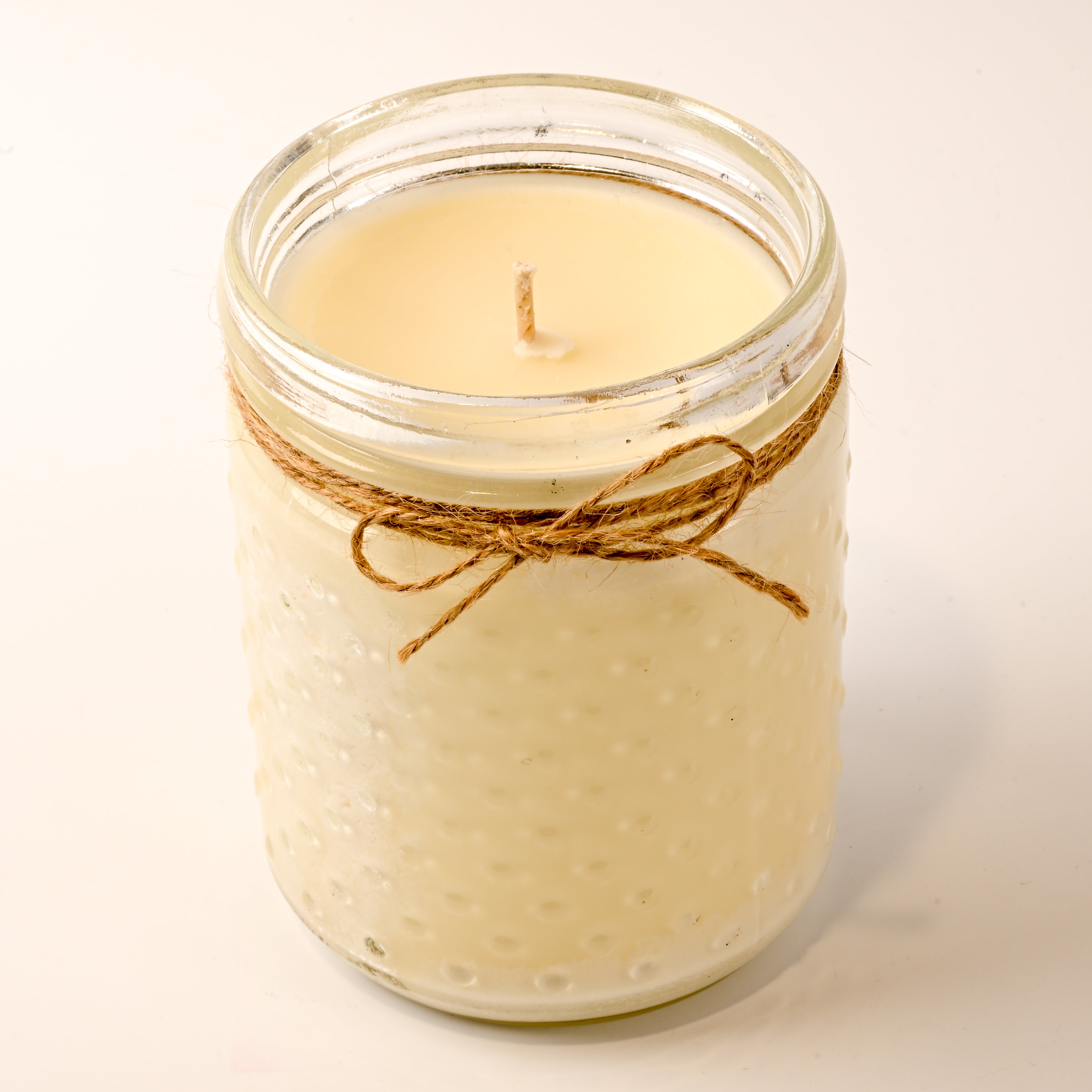 Candle in a glass jar with twine on a white background