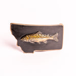 Metallic fish emblem on a black Montana-shaped belt buckle on a white background