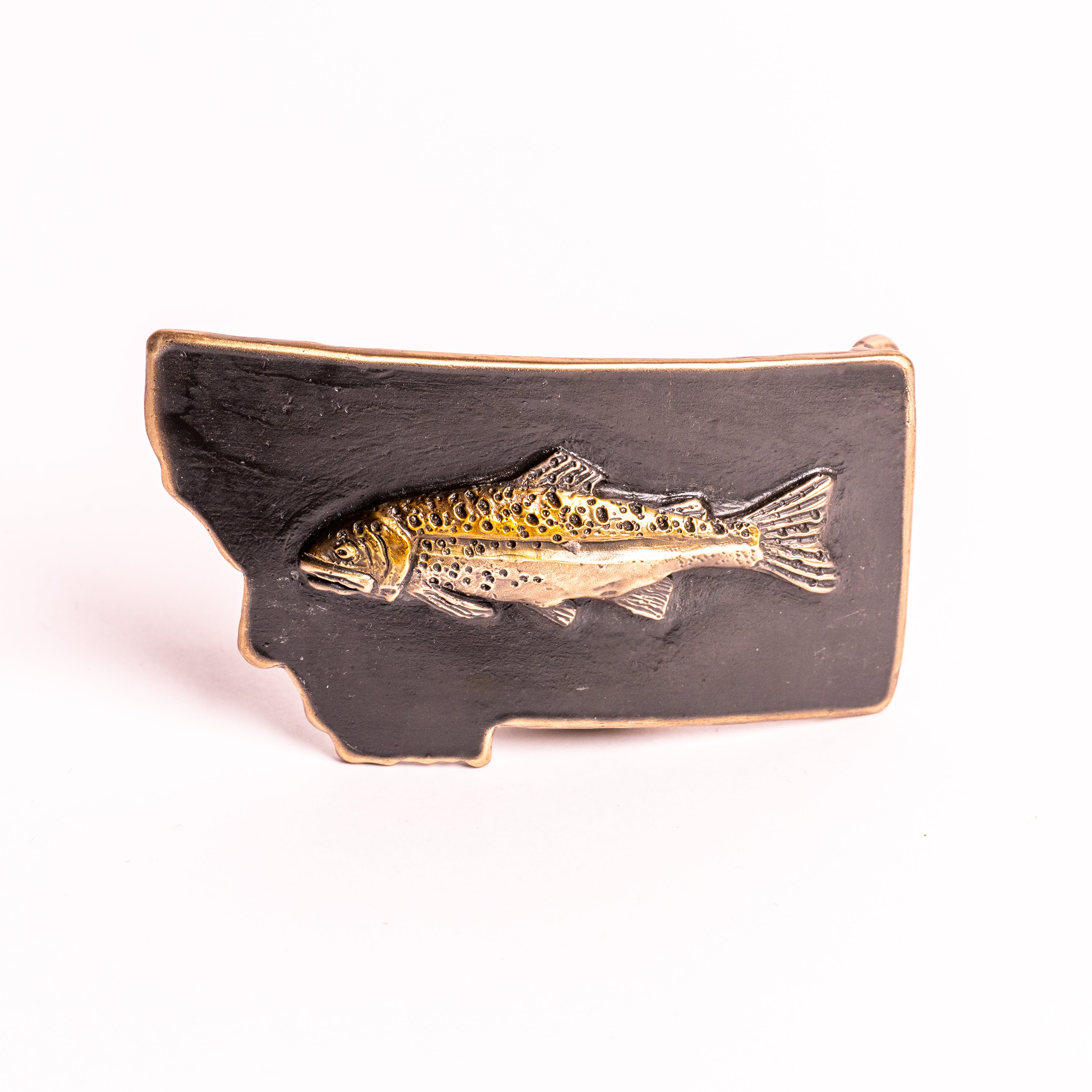 Metallic fish emblem on a black Montana-shaped belt buckle on a white background
