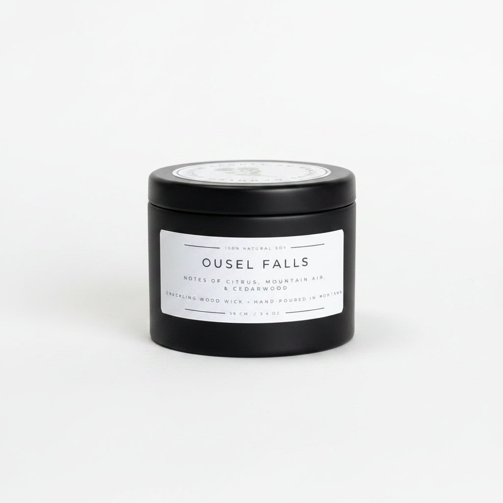 A black cylindrical candle tin with a white label reading 'OUSEL FALLS' sits on a white background