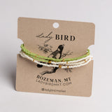 Three beaded bracelets in light green, white, and gold tones displayed on a brown kraft card labeled Lady Bird, photographed against a light neutral background.