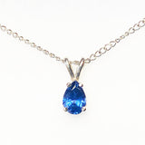 A silver chain necklace with a pear-cut blue gemstone pendant in a silver setting, shown against a plain white background.
