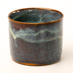 Ceramic pot with a textured blue and brown glaze on a white background