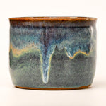 Ceramic pot with blue and brown glaze on a white background