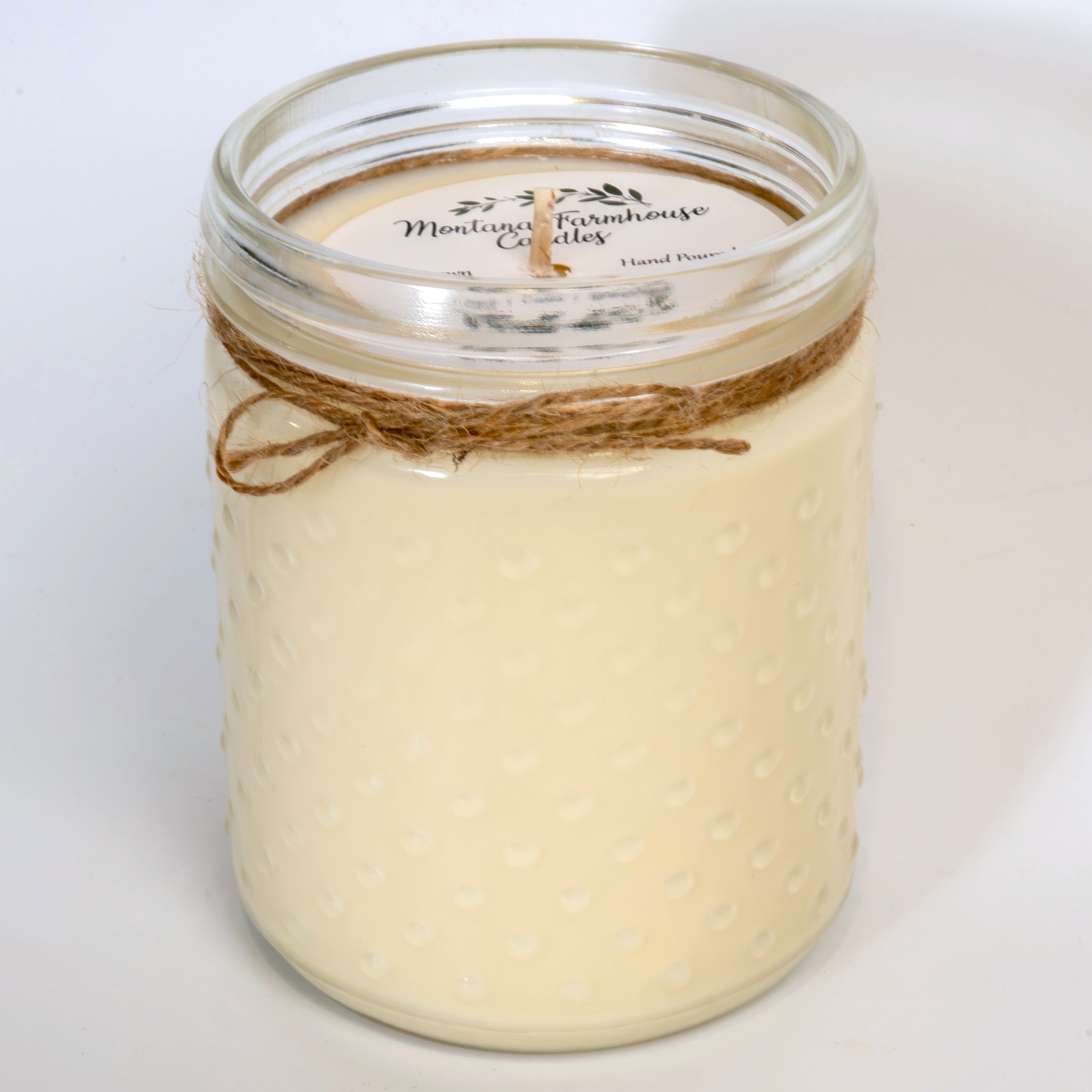 Jar candle with twine wrapping on a white background