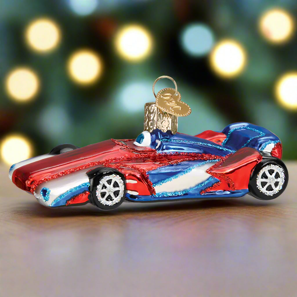 Glass ornament of a red and blue race car on a white background