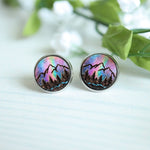 Pair of round earrings with mountain design on a light background