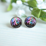 Pair of round earrings with mountain design on a light background