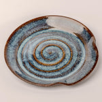 Ceramic plate with spiral design on a beige background