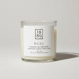 Candle with a label featuring the number 1889 and product details on a white background
