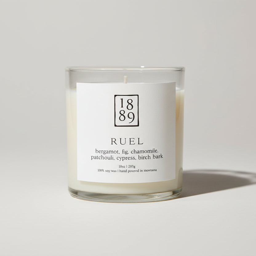 Candle with a label featuring the number 1889 and product details on a white background