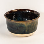 Black ceramic bowl with yellow accents on a white background