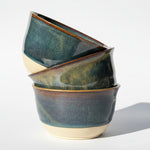 Stack of ceramic bowls with a rustic finish on white background