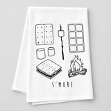 A white kitchen towel with black line art illustrations of s'mores (graham crackers, marshmallows, ice cream, s'more stack, campfire) and the text 'S'MORE' at the bottom, laid flat on a wooden surface.