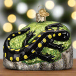 Glass ornament of a black salamander with yellow spots on a green background