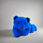 Blue teddy bear on a white surface with a gray background