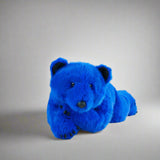 Blue teddy bear on a white surface with a gray background
