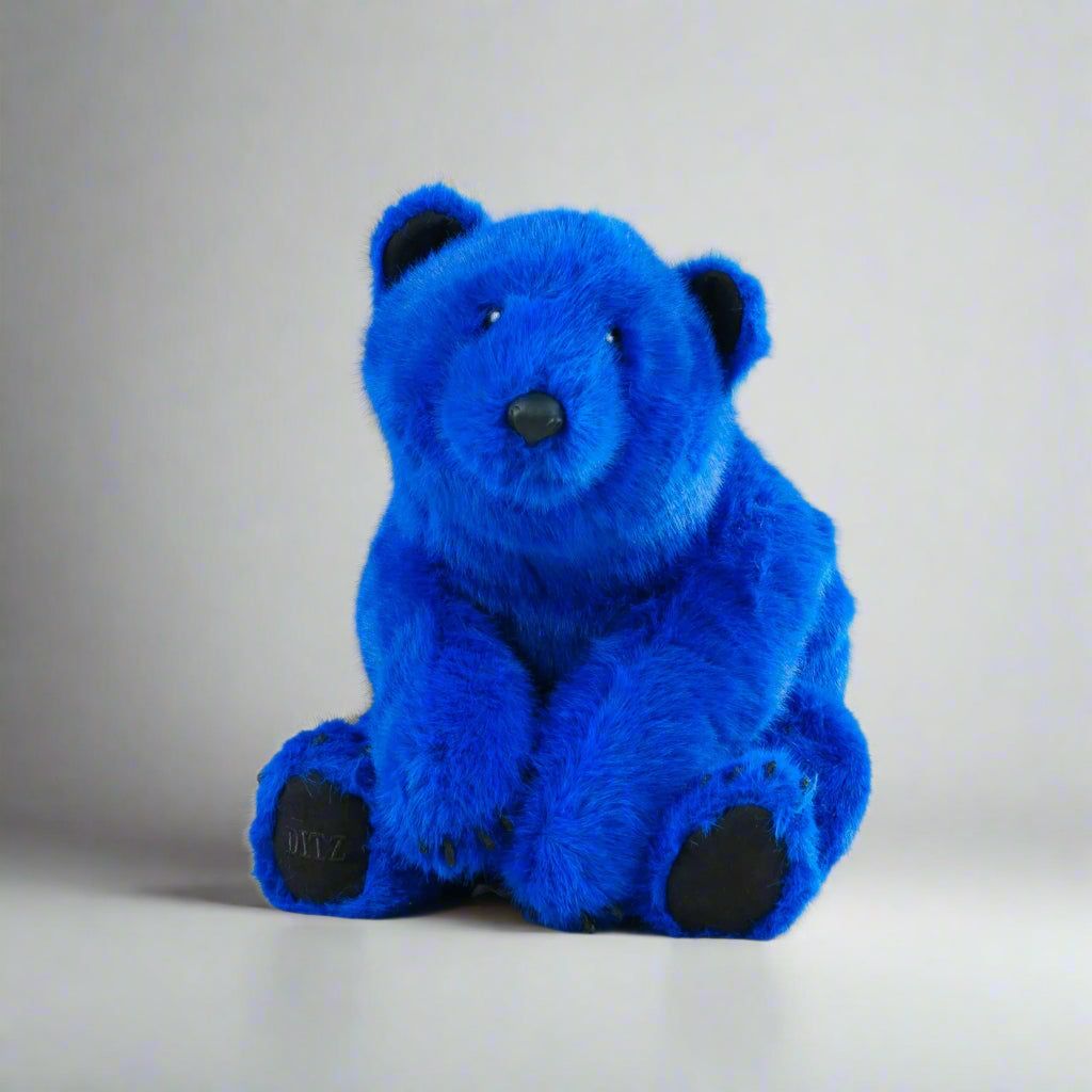 Blue teddy bear on a white surface with a gray background