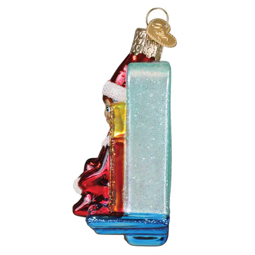 Christmas ornament with an elf by a decorated tree on a white 