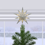 Decorative star tree topper on a Christmas tree with a snowy window background