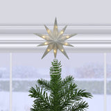 Decorative star tree topper on a Christmas tree with a snowy window background