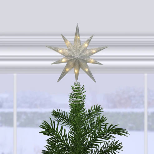 Decorative star tree topper on a Christmas tree with a snowy window background