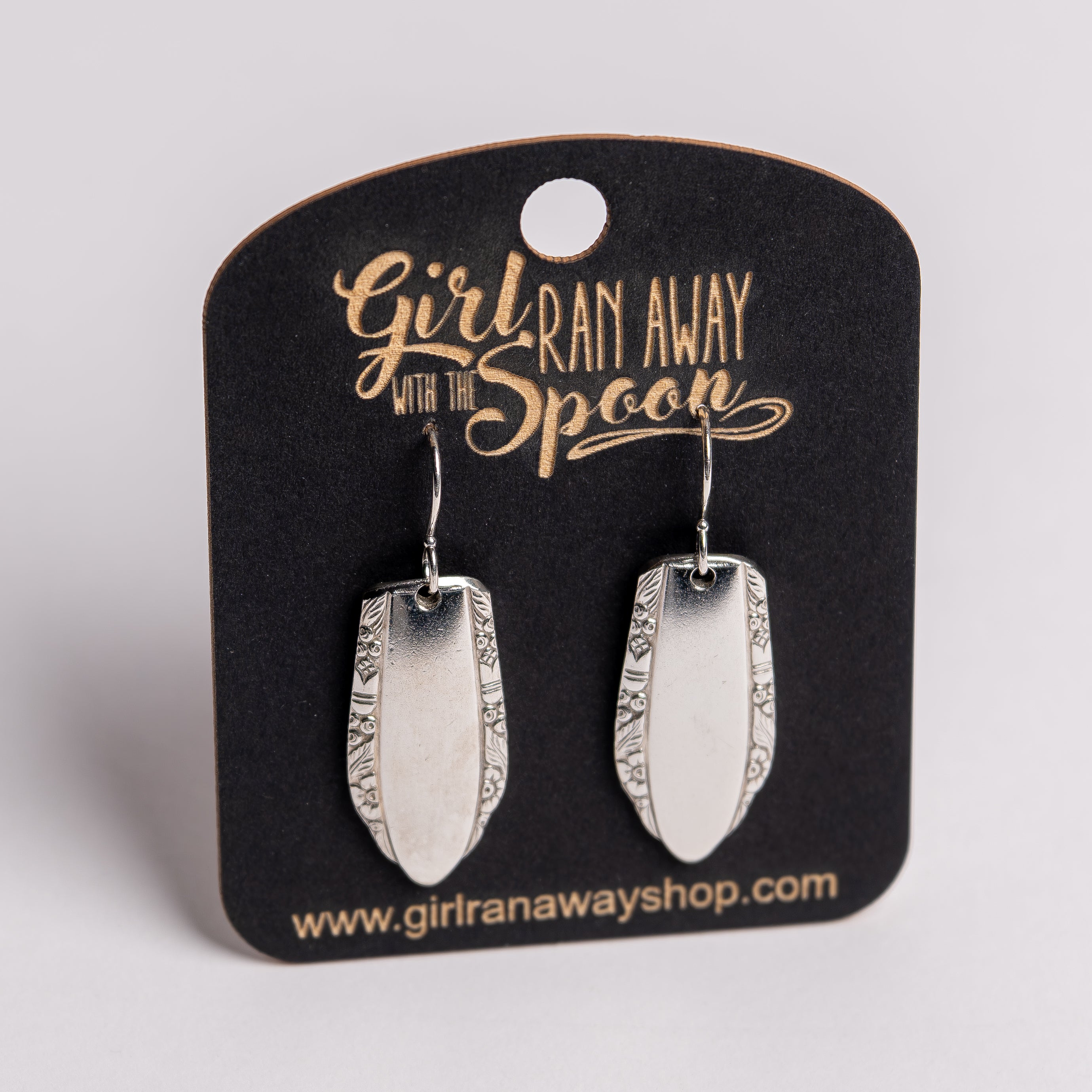Silver earrings on a 'Girl Run Away with the Spoon' branded card.