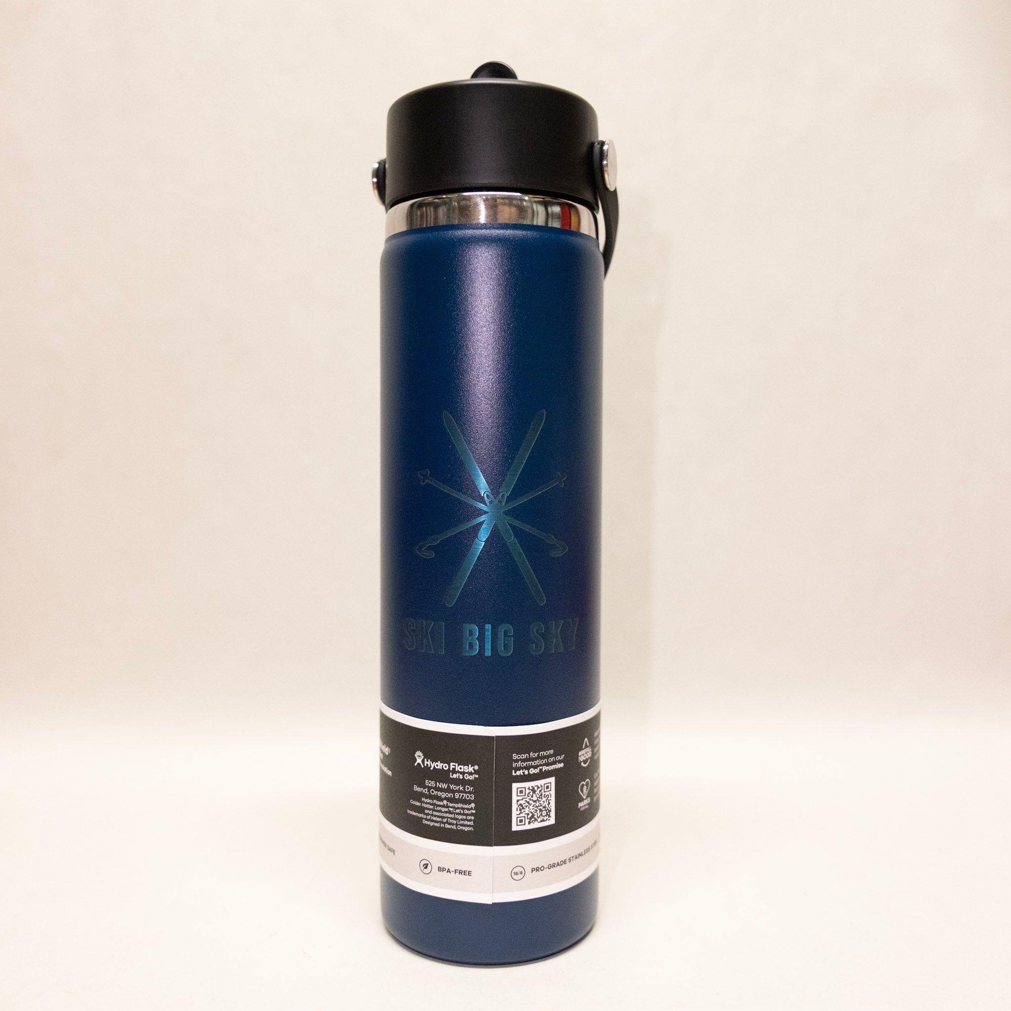 Blue insulated bottle with black lid on a beige background