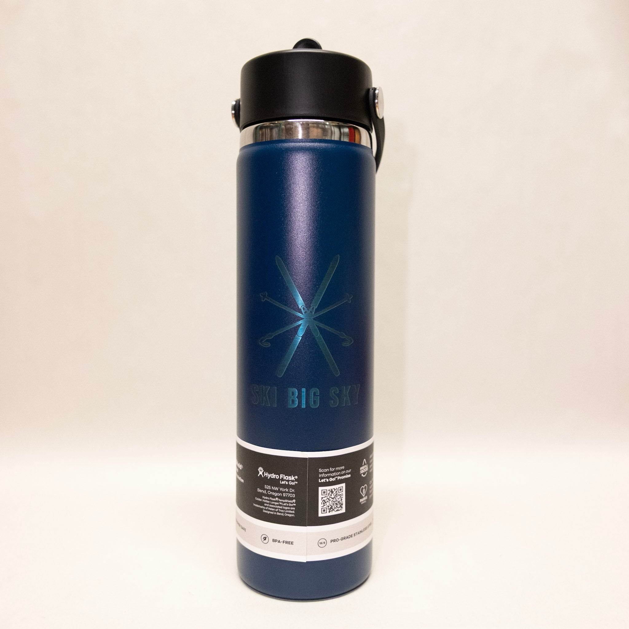 Blue insulated bottle with black lid on a beige background